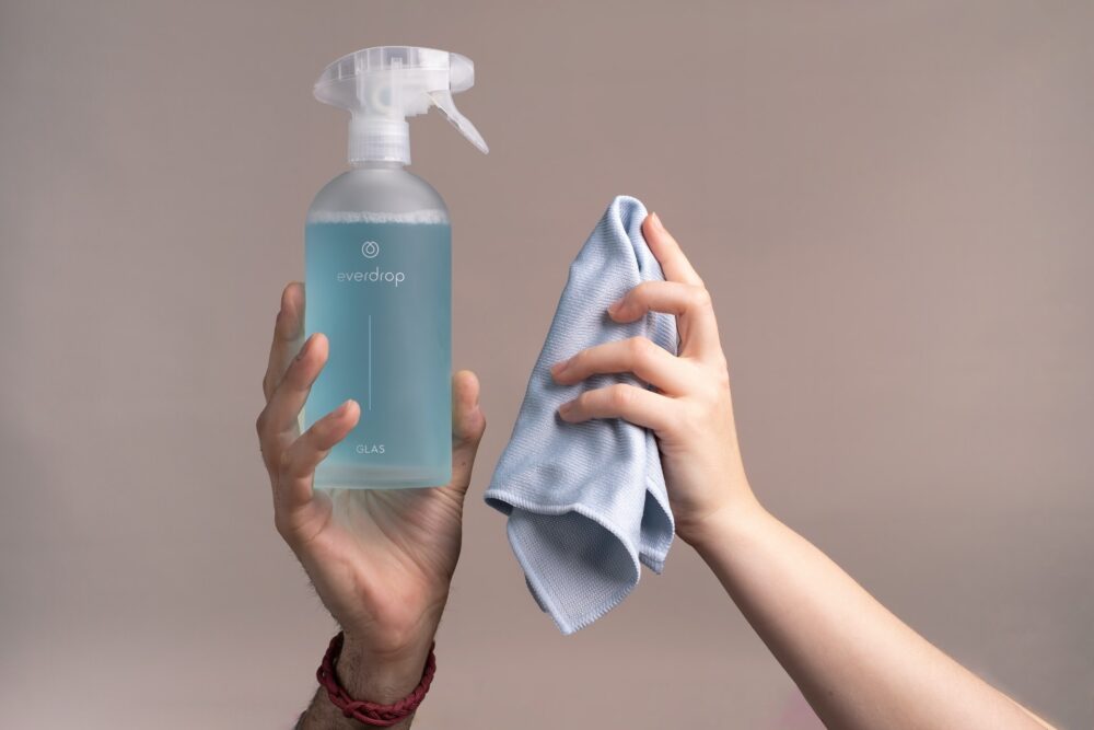 person holding cleaning agent and microfiber