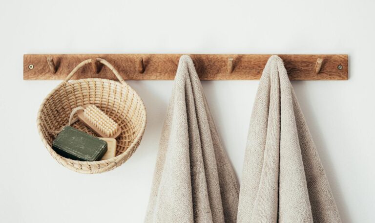 Wooden hanger with towels and basket with bathroom products