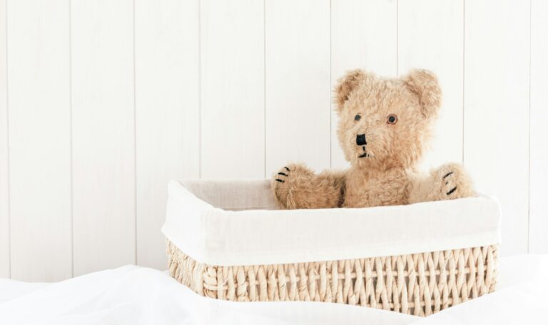 a teddy bear sitting in a basket on a bed