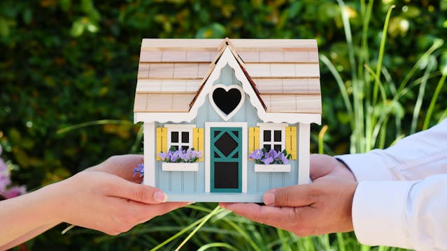 people-holding-miniature-wooden-house